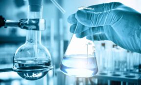 hand of scientist holding flask with lab glassware in chemical laboratory background, science laboratory research and development concept